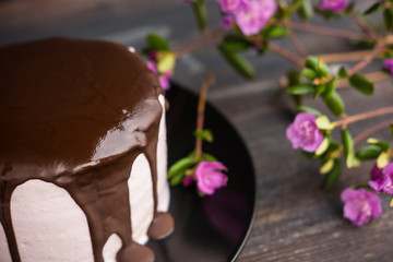 Pink creamy cake with flowers on the wooden background. Selective focus.