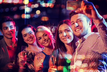 friends taking selfie by smartphone in night club
