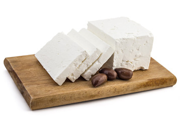 Sliced fresh white cheese from cow's milk with kalamata black olives on wooden board and white...
