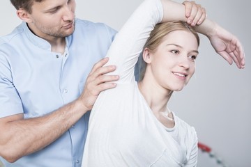 Physiotherapist stretching woman's arm