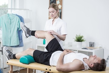 Obraz na płótnie Canvas Chiropractor exercising man's leg