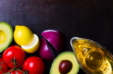 Ingredients for sauce guacamole - avocado, tomatoes, lemon, onion, oil on black background