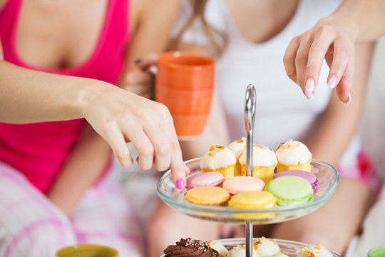 friends or teen girls eating sweets at home