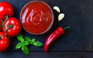 Fresh tomatoes, red chili, and garlic presented with rich tomato sauce on a dark background