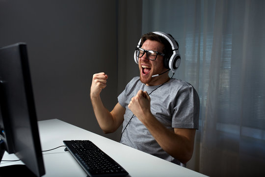 man in headset playing computer video game at home