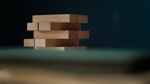 Closeup hand girl take one block on the tower from wooden blocks, dark tone.