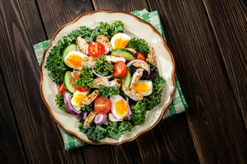 Fresh salad with chicken, tomatoes, eggs and lettuce on plate