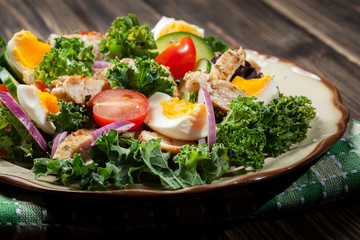 Fresh salad with chicken, tomatoes, eggs and lettuce on plate