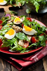 Fresh salad with chicken, tomatoes, eggs and arugula on plate