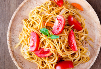 Pasta spaghetti with tomatoes, cheese and basil on rustic wooden background