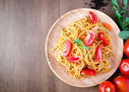 Pasta spaghetti with tomatoes, cheese and basil on rustic wooden background