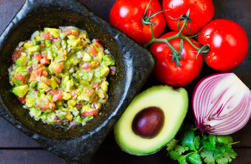 Latin American mexican sauce guacamole and ingredients - avocado, tomatoes, onion, cilantro