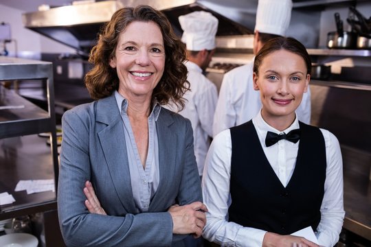 Restaurant manager and waitress smiling in commercial kitchen