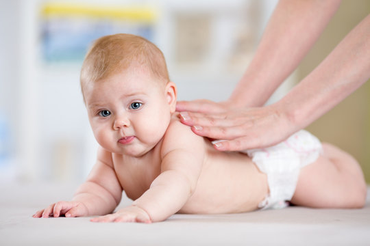 Mother or therapist makes massage to her baby at home. Health care and medicine concept.