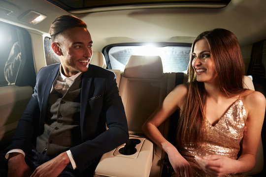 Young couple in the back of a limo looking at each other