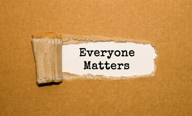 The text Everyone Matters appearing behind torn brown paper