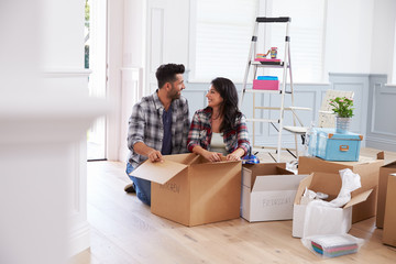 Hispanic Couple Moving Into New Home And Unpacking Boxes
