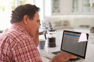 Fototapeta na wymiar Confused Senior Hispanic Man Sitting At Home Using Laptop
