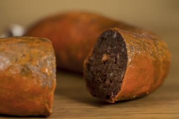 Close-up of traditional homemade blood sausage, covered by red lard, on wooden table