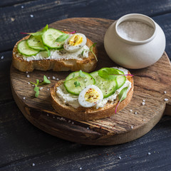 Healthy delicious breakfast or snack - open sandwich with goat's cheese and cucumber and boiled quail eggs
