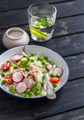 Fresh salad with cous cous, vegetables and baked salmon. Healthy tasty food. On a dark wooden background
