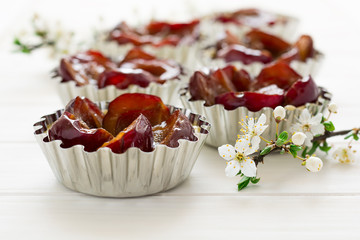 Raw tartlets with plums on white wooden background
