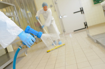 Workers cleaning down factory floor