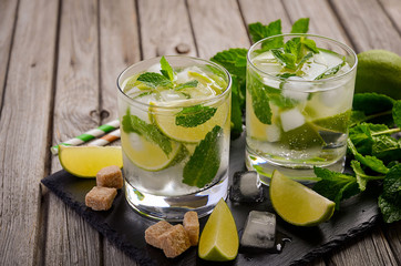 Fresh mojito cocktail with lime and mint on rustic wooden background