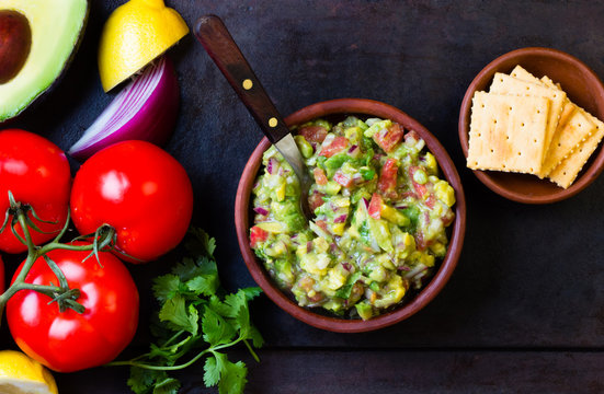 Mexican Latin American sauce guacamole and ingredients - avocado, tomatoes, onion, lemon, cilantro