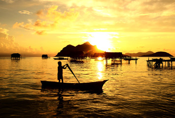 Silhouette of a kid paddling on a boat near Bajau Laut village in Maiga Island in Semporna, Sabah...