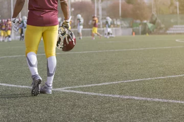 Foto op Plexiglas American football sportsman player holding helmet and walking on the field © zphoto83