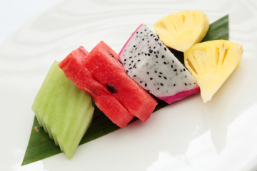 slices of watermelon and fruits on a palm leaf