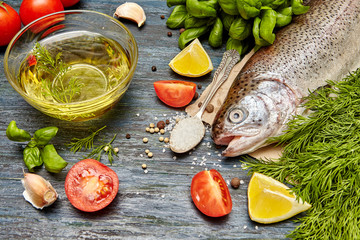 Raw trout and ingredients for cooking on a  dark wooden background. Healthy food  concept
