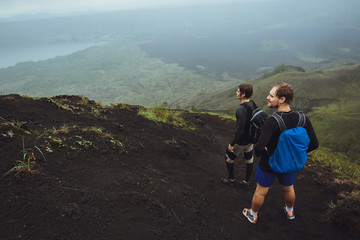 3 Men walk along the hill with backpacks and with white clouds a