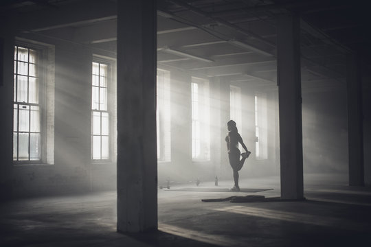 Woman stretching in dark gym
