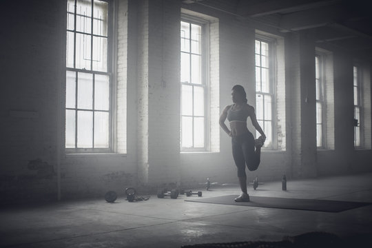 Black woman stretching in dark gym