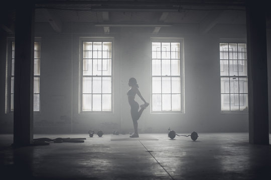Black woman stretching in dark gym