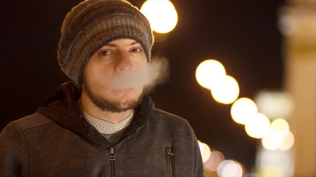 Man smoking e-cigarette outdoor at night
