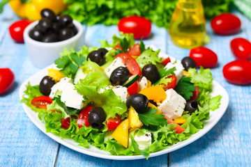 Greek salad with fresh vegetables, feta cheese and black olives on a wooden background