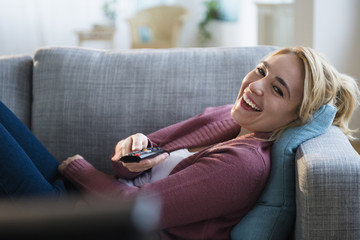 Caucasian woman watching television on sofa