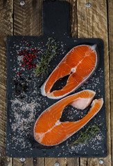 Two fresh raw salmon or trout steaks with salt, peppers and thyme