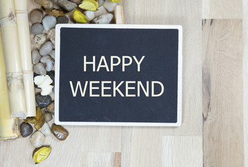 happy weekend on chalkboard with a bamboo and pebbles envelope notes against wooden background - office abstract. Retro design