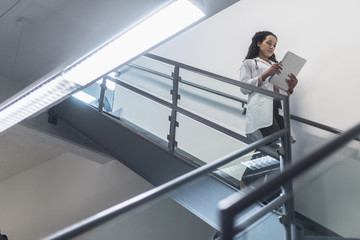 Low angle view of mixed race doctor reading medical chart on staircase