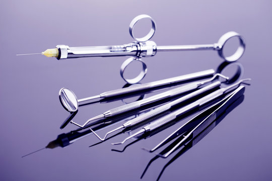 Dental syringe, mirror and other tools on shiny table