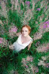 Beautiful woman in white dress among magic giant flowers.