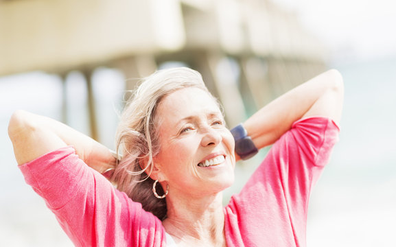 Older Caucasian Woman With Hands Behind Head On Beach