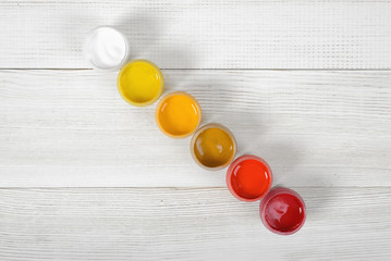 Light colors of gouache jars are diagonally on white background in top view