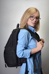 Portrait of a young woman with backpack over gray background