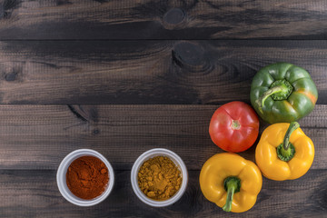 green and yellow paprika with tomato and chili powder on wooden background