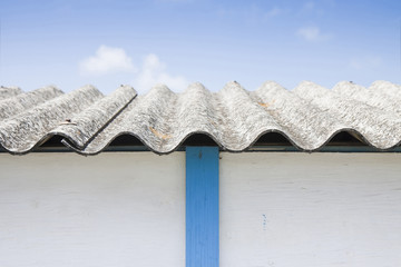 Dangerous asbestos roof detail against a blue sky